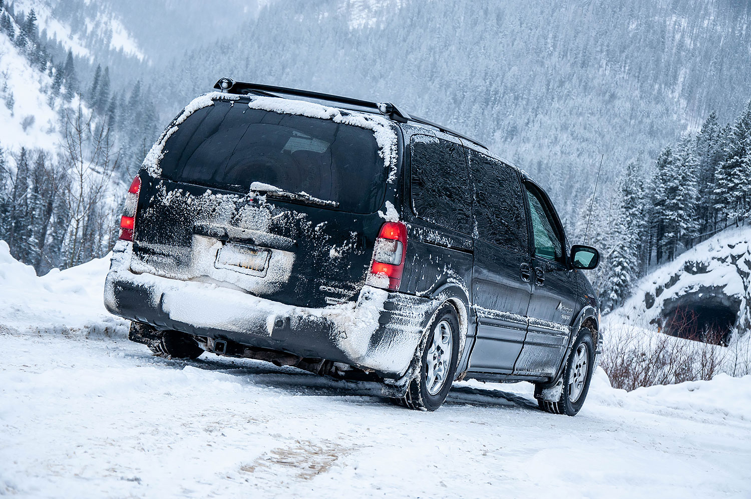 2003 AWD Pontiac Montana Thunder during winter driving in the mountains, covered with snow and ice, three quarter rear view